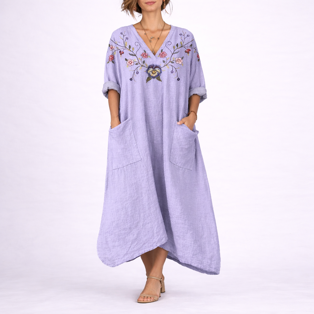 Purple - Model wearing a woven paisley print relaxed midaxi dress with a v-neckline, rolled sleeves, large front buttons, and patch pockets.