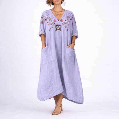 Purple - Model wearing a woven paisley print relaxed midaxi dress with a v-neckline, rolled sleeves, large front buttons, and patch pockets.