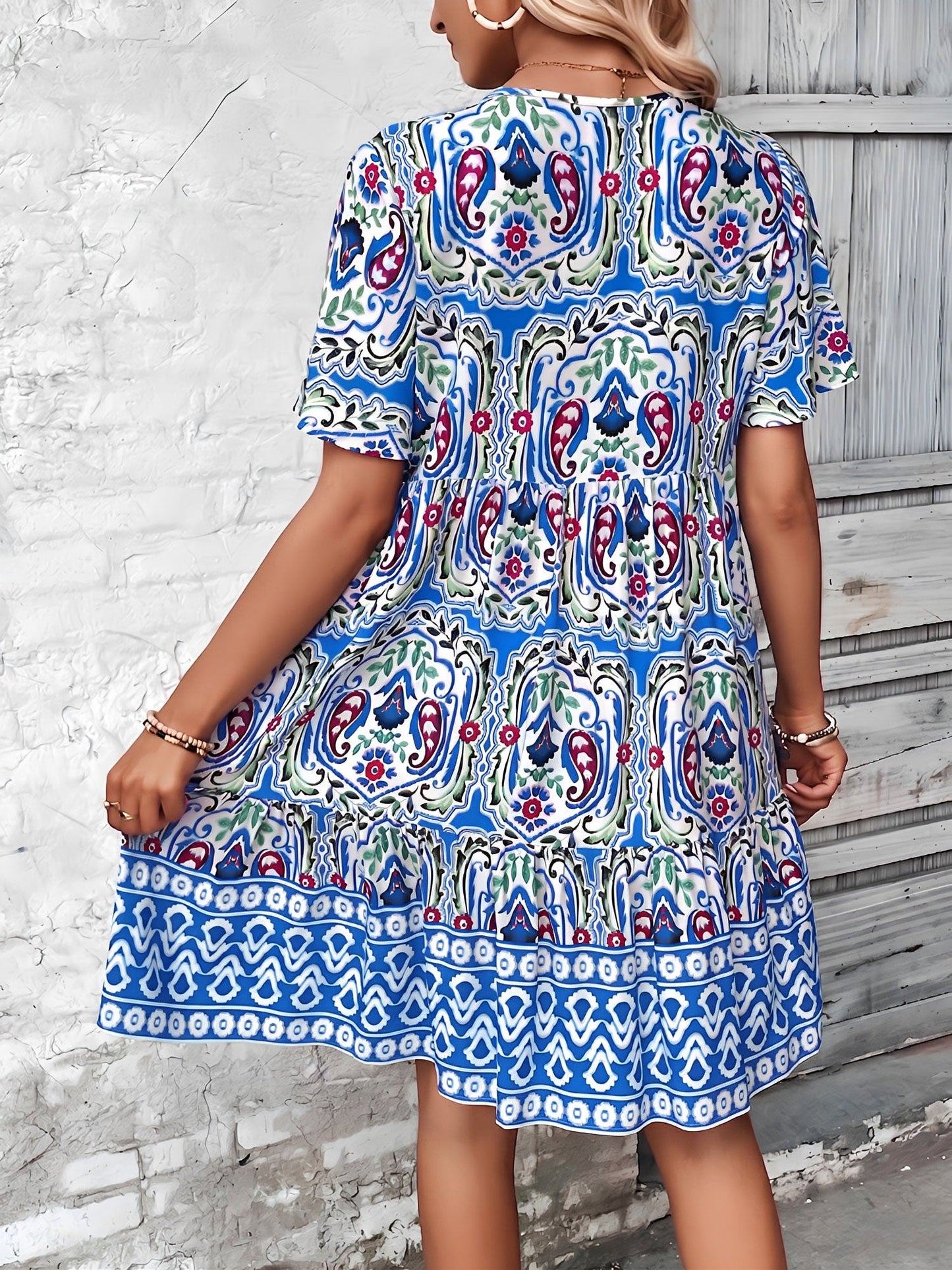 Blue - Woman wearing a woven paisley print V-neck tiered mini dress with short sleeves and front button detailing.