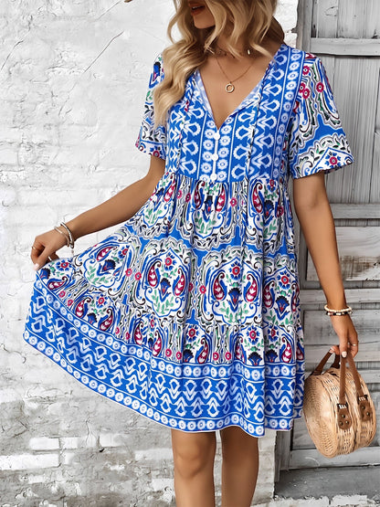 Blue - Woman wearing a woven paisley print V-neck tiered mini dress with short sleeves and front button detailing.