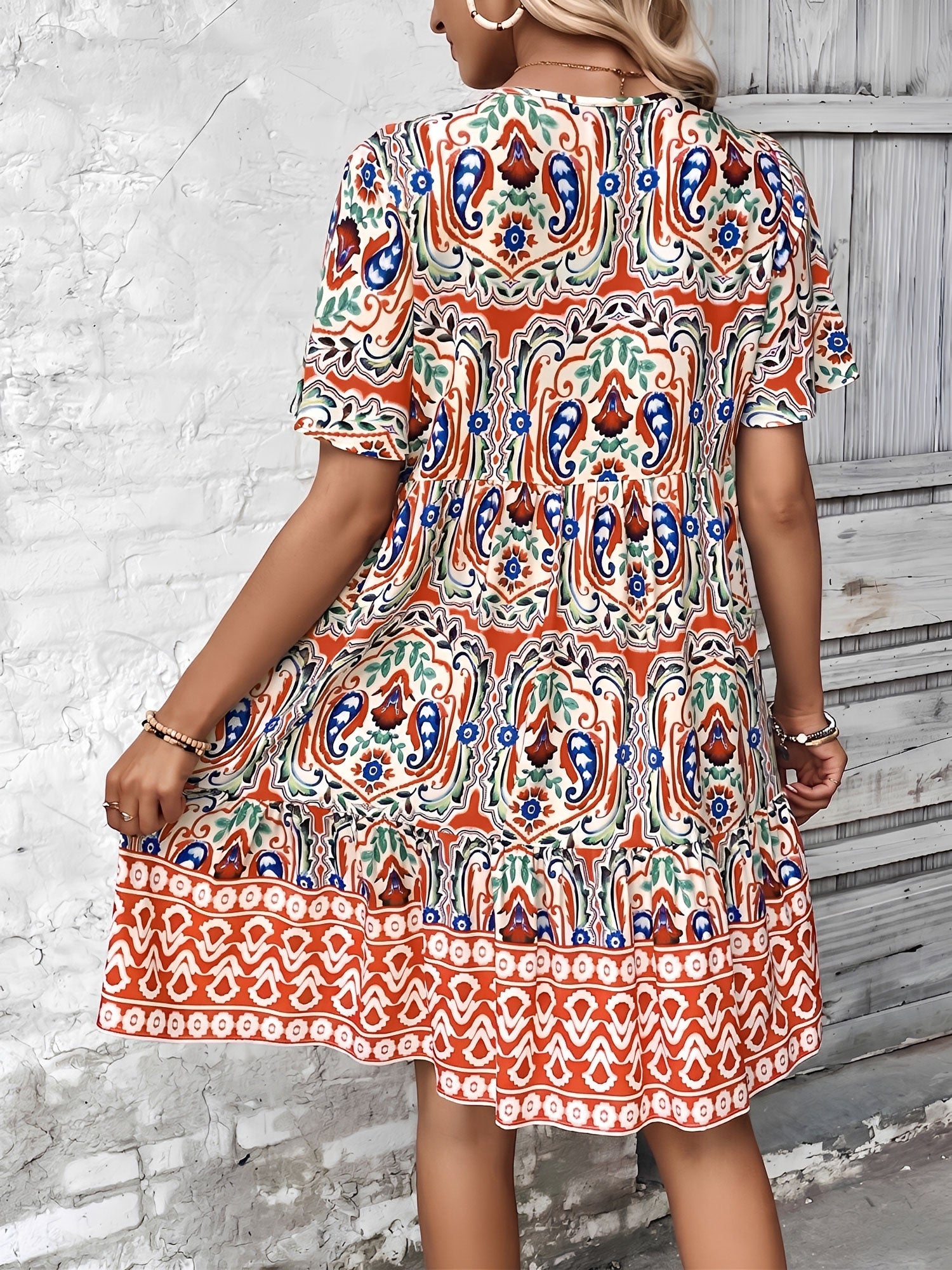 Orange - Woman wearing a woven paisley print V-neck tiered mini dress with short sleeves and front button detailing.