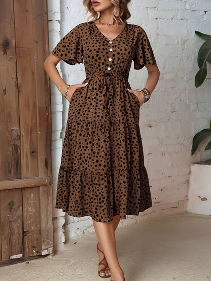 Leopard - Woman wearing a spot pattern V-neck tiered midi dress with short sleeves and side pockets, standing in an architectural hallway.
