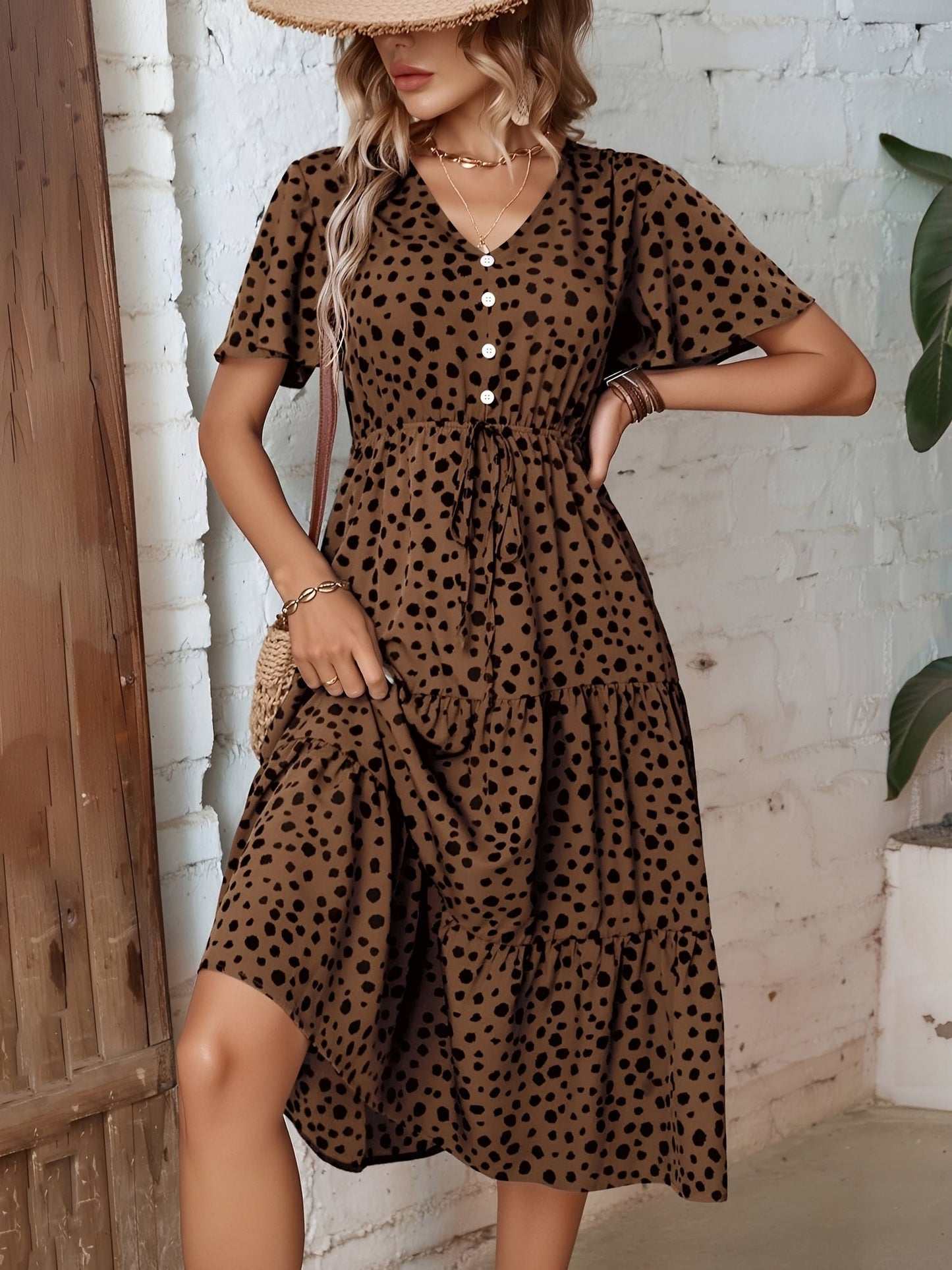 Leopard - Woman wearing a spot pattern V-neck tiered midi dress with short sleeves and side pockets, standing in an architectural hallway.