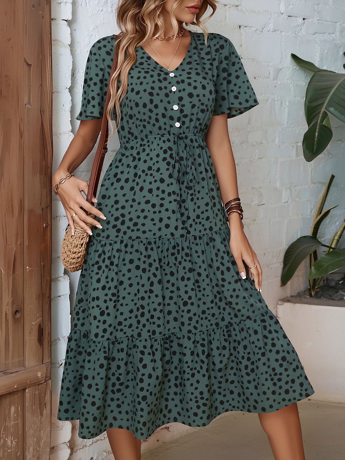 Dark Green - Woman wearing a spot pattern V-neck tiered midi dress with short sleeves and side pockets, standing in an architectural hallway.