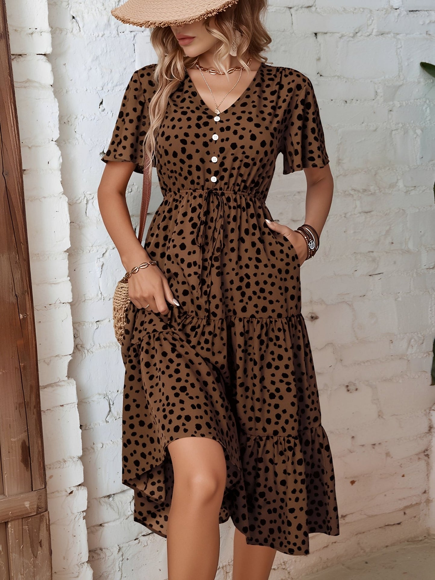 Leopard - Woman wearing a spot pattern V-neck tiered midi dress with short sleeves and side pockets, standing in an architectural hallway.
