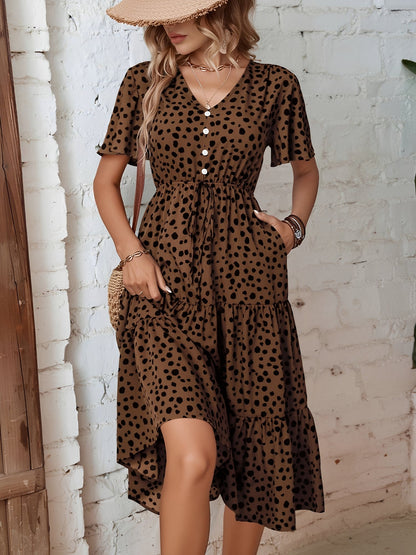 Leopard - Woman wearing a spot pattern V-neck tiered midi dress with short sleeves and side pockets, standing in an architectural hallway.