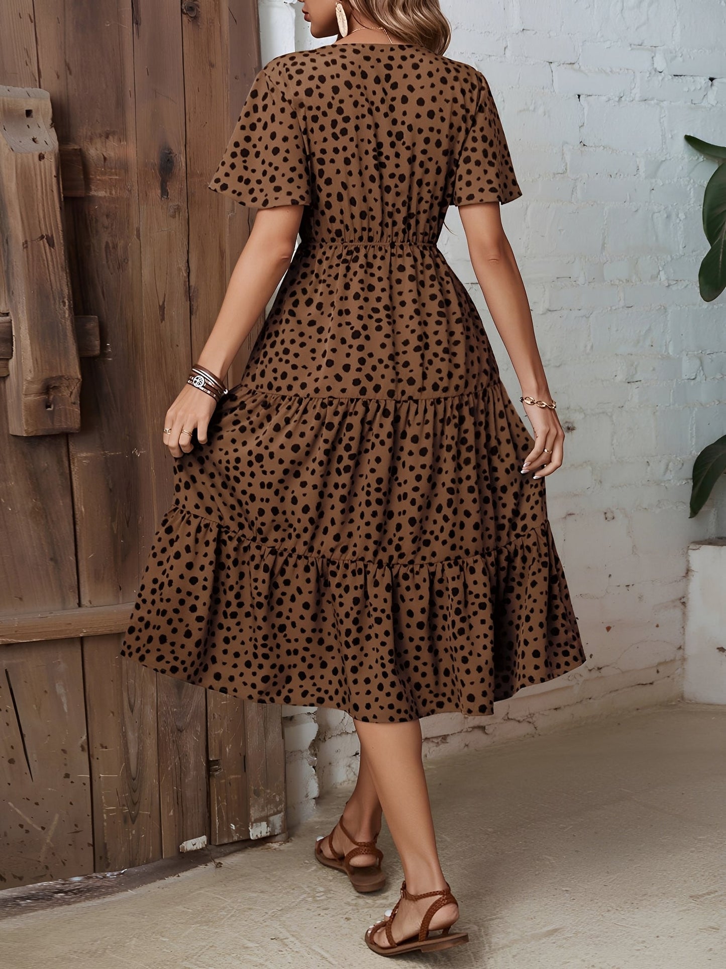 Leopard - Woman wearing a spot pattern V-neck tiered midi dress with short sleeves and side pockets, standing in an architectural hallway.