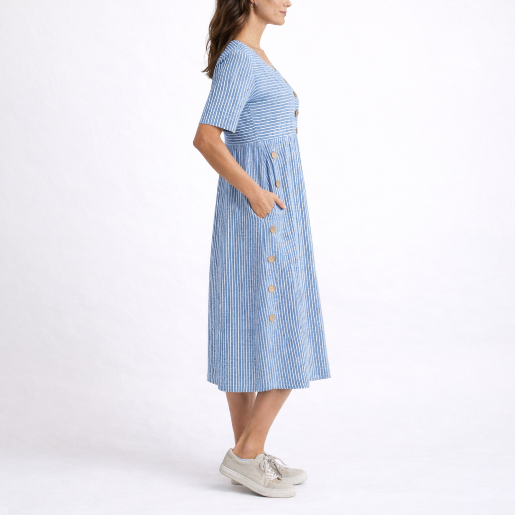 Blue - Woman wearing a striped short-sleeve midi dress with asymmetric wooden button detailing and side pockets, standing against a white background.