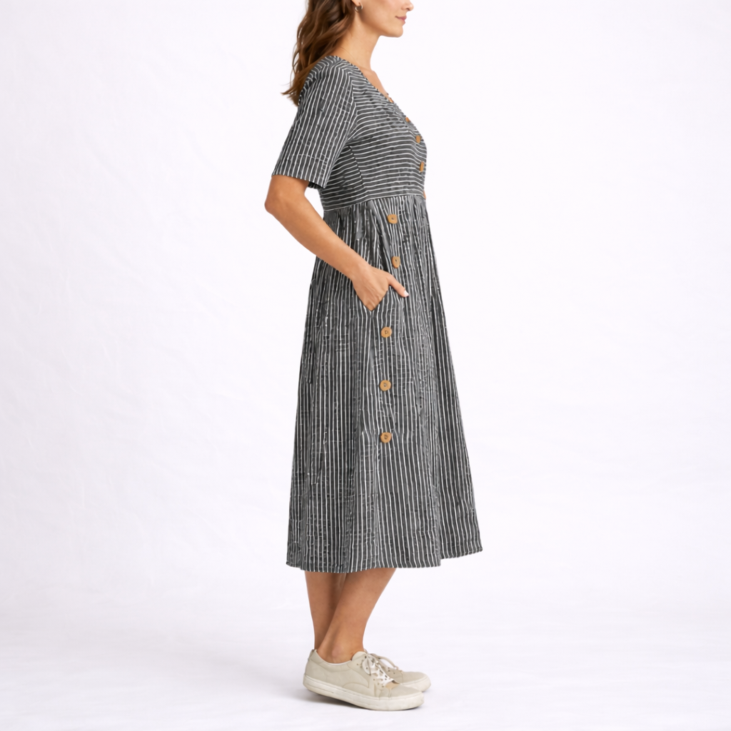 Gray - Woman wearing a striped short-sleeve midi dress with asymmetric wooden button detailing and side pockets, standing against a white background.