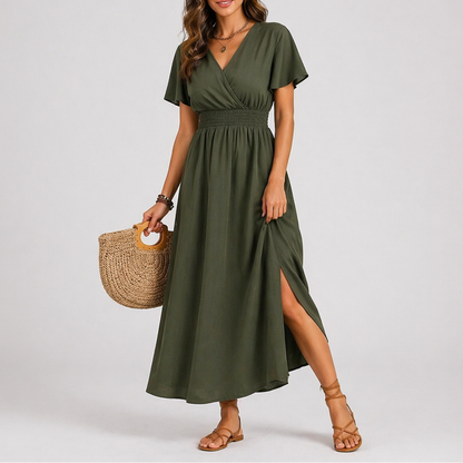 Olive green - A woman modelling a woven V-neck maxi dress featuring short flutter sleeves, a shirred waistline, and a side split, styled with sandals and a woven handbag.